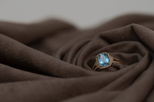 Close-up of a luxurious aquamarine ring set against rich brown fabric, perfect for elegance and style.