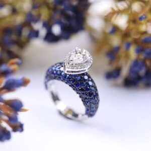 A close-up of a luxurious diamond and sapphire ring against a floral backdrop, highlighting elegance.