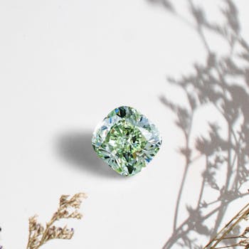 Close-up of a green diamond with shadow of plants, exuding luxury and elegance.